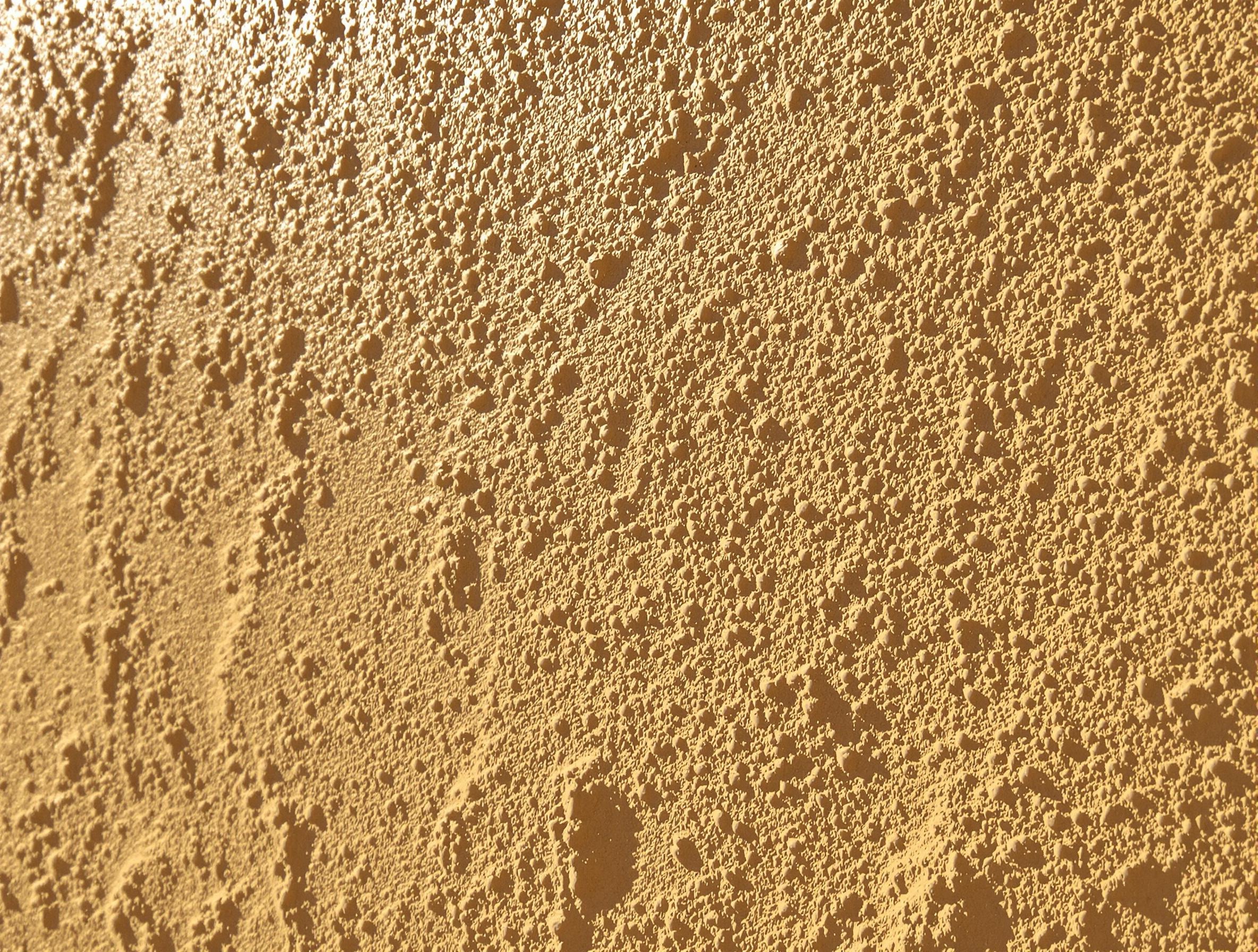 Enduit naturel appliqué sur un mur en torchis de couleur ocre chaude.