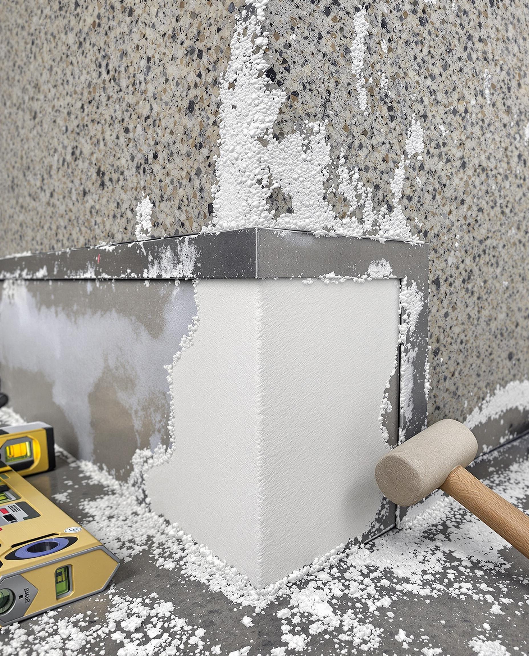 Pose d'une cornière métallique sur un angle de façade en granit avant application d'enduit