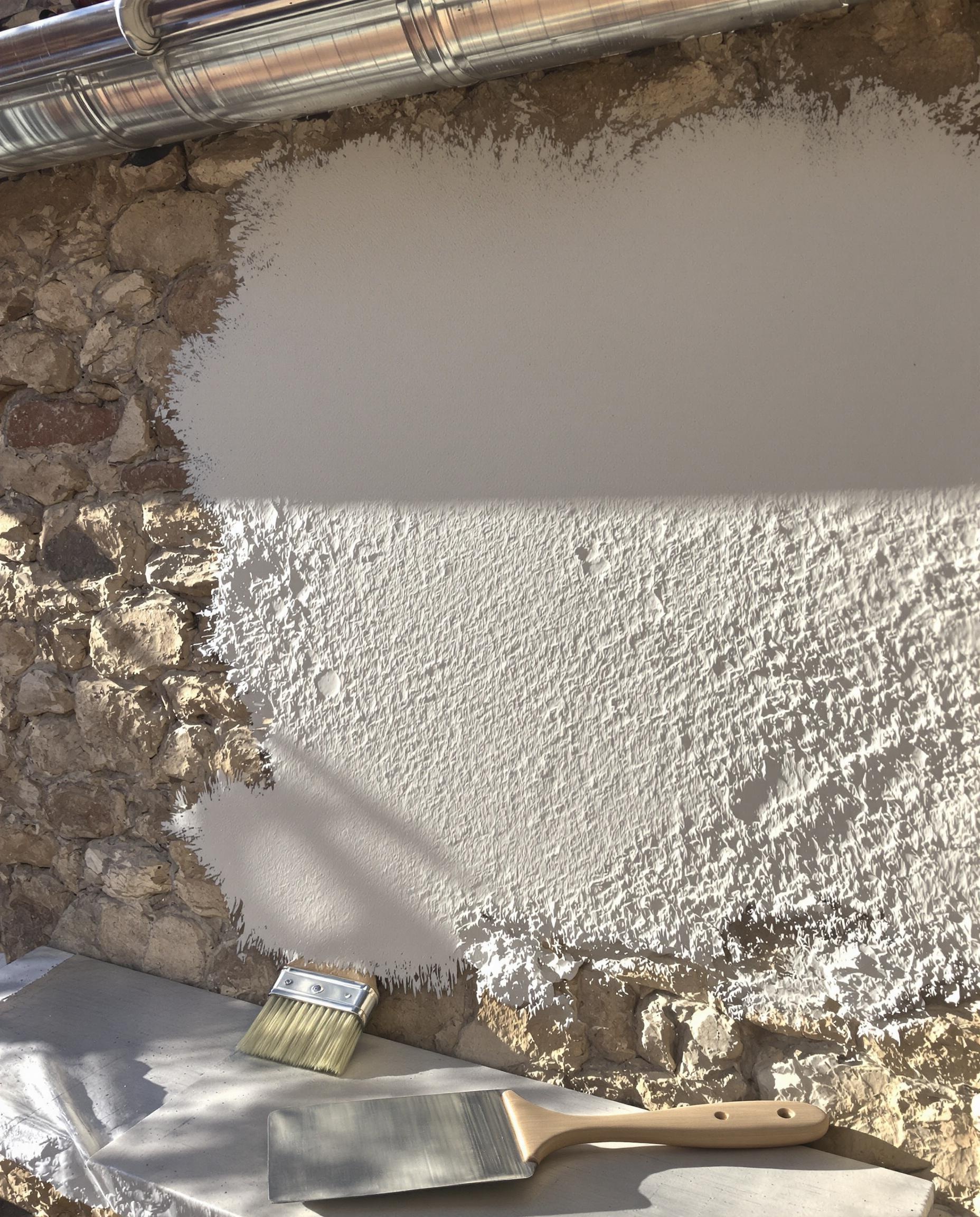 Application d'un badigeon à la chaux sur un mur en pierre