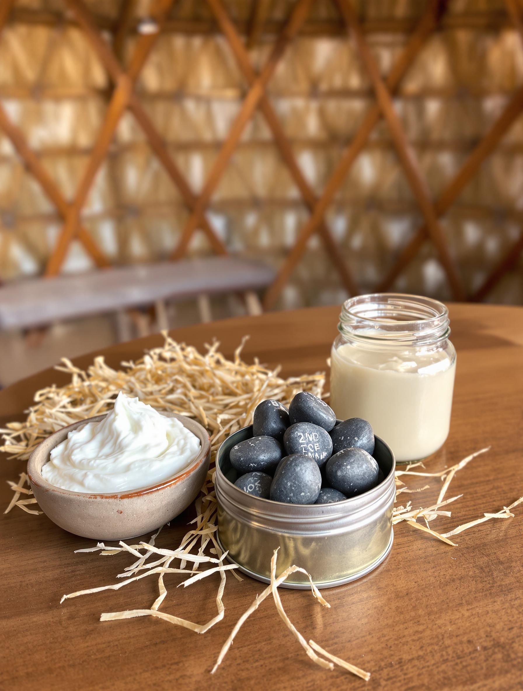 Trois styles de dentifrices DIY bretons : pâte blanche dans un bol en bois, galets solides dans une boîte vintage, et baume onctueux dans une yourte en paille